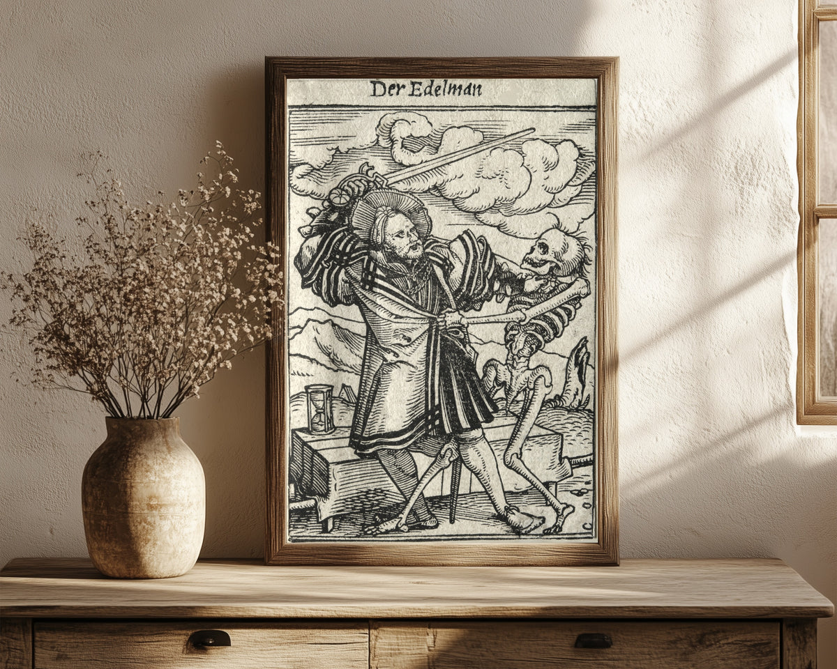 Framed art print of The Dance of Death: Der Edelman (The… by Hans Holbein the Younger, in a dark wood frame leaning on a rustic console beside dried flowers