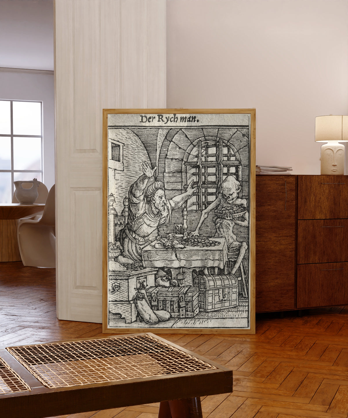 Framed art print of The Dance of Death: Der Rych man (The Miser) by Hans Holbein the Younger, in a light wood frame leaning in a warm room with a parquet floor