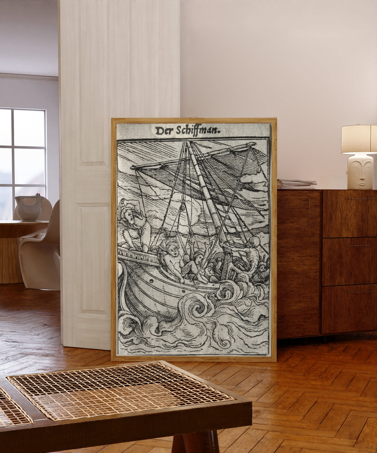 Framed art print of The Dance of Death: Der Schiffman (The… by Hans Holbein the Younger, in a light wood frame leaning in a warm room with a parquet floor