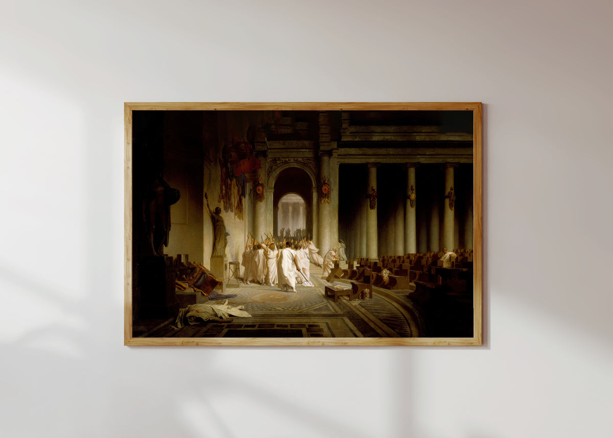 Framed art print of The Death of Caesar by Jean-Léon Gérôme, in a light wood frame on a sunlit white wall