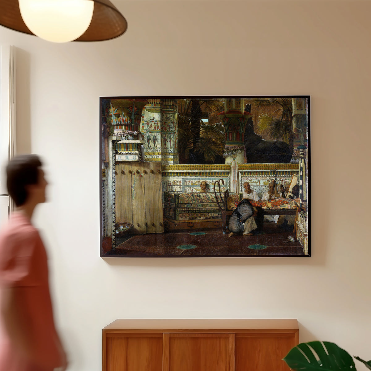 Framed art print of The Egyptian Widow by Lawrence Alma-Tadema, in a slim black frame on a warm wall in a sunlit room