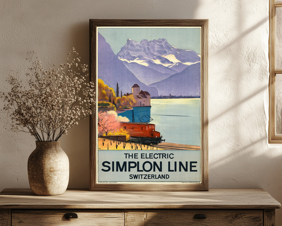 Framed art print of The Electric Simplon Line: Switzerland by Emil Cardinaux, in a dark wood frame leaning on a rustic console beside dried flowers