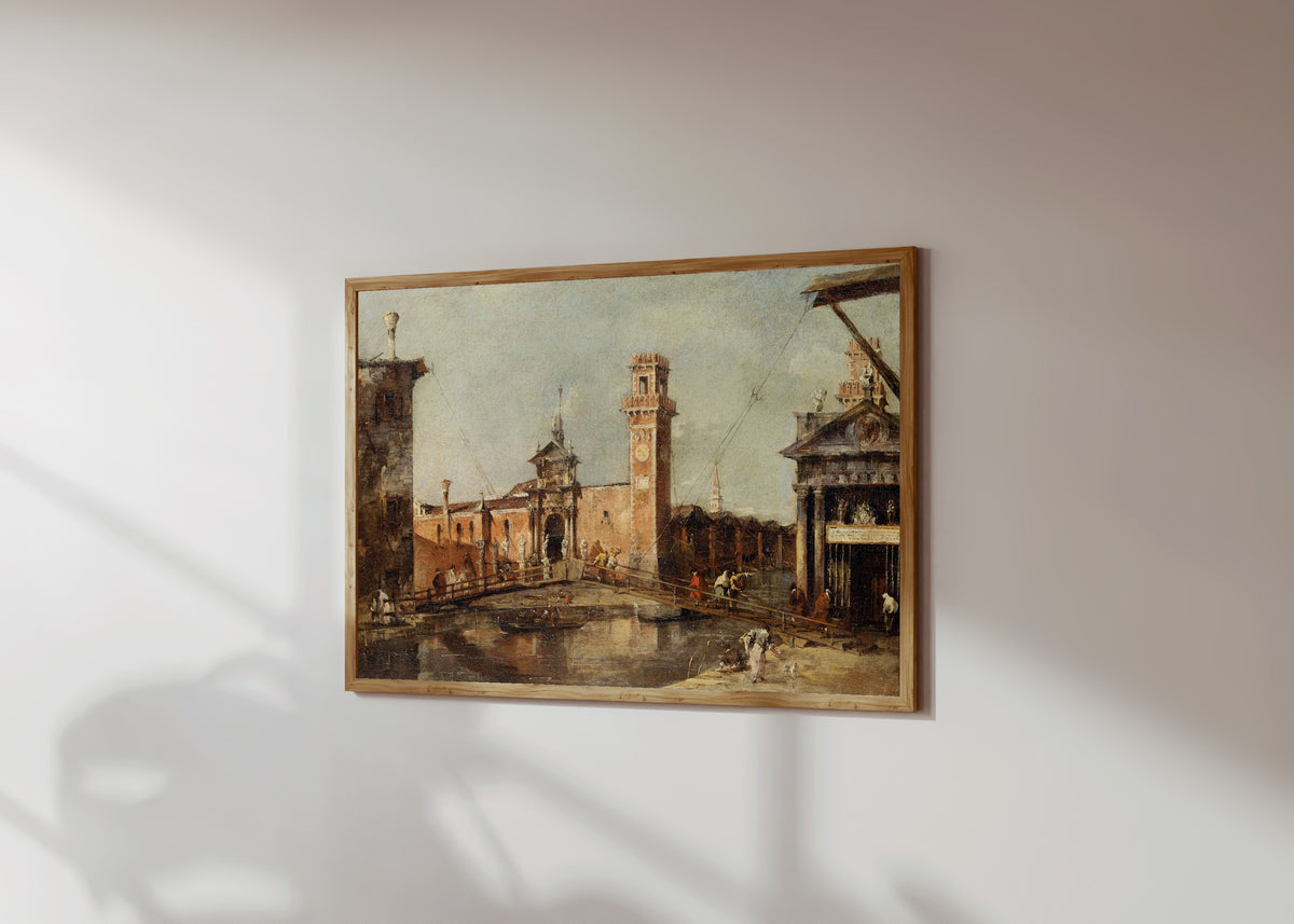 Framed art print of The Entrance to the Arsenal in Venice by Francesco Guardi, in a light wood frame on a sunlit white wall, seen at a slight angle