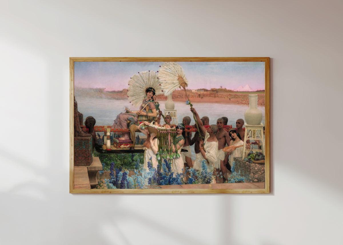 Framed art print of The Finding of Moses by Lawrence Alma-Tadema, in a light wood frame on a sunlit white wall