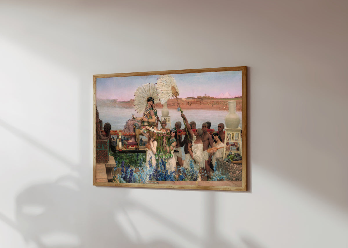 Framed art print of The Finding of Moses by Lawrence Alma-Tadema, in a light wood frame on a sunlit white wall, seen at a slight angle