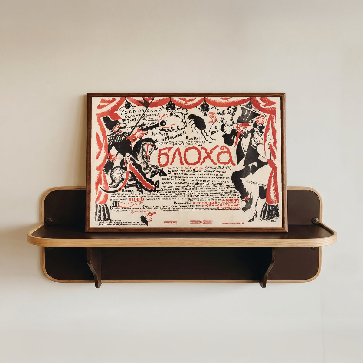 Framed art print of The Flea (Moscow Art Theatre production) by Boris Kustodiev, in a dark wood frame resting on a wall shelf