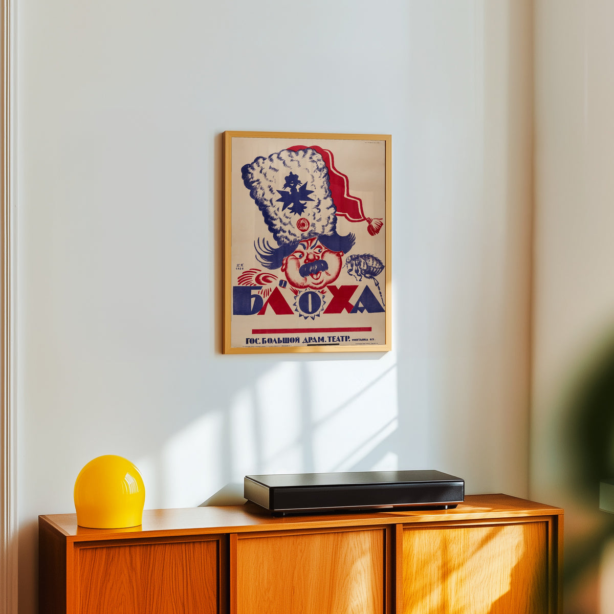 Framed art print of The Flea by Boris Kustodiev, in a light wood frame on a white wall above an orange sideboard