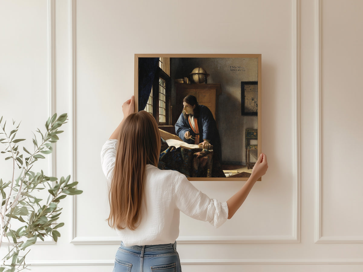 Framed art print of The Geographer by Johannes Vermeer, hung on a panelled wall