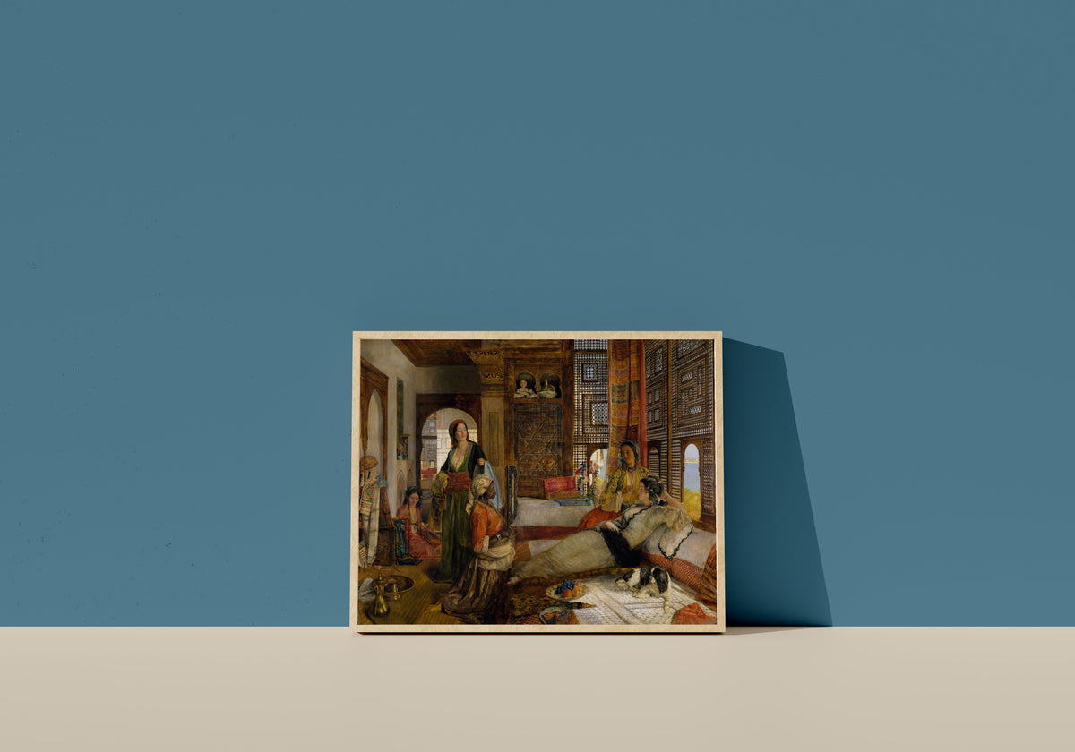 Framed art print of The Harem by John Frederick Lewis, in a light wood frame leaning on a blue wall