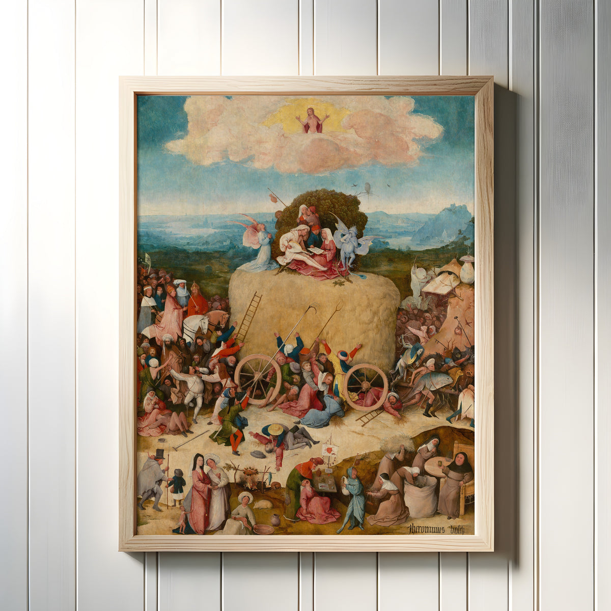 Framed art print of The Haywain Triptych (central panel) by Hieronymus Bosch, in a light wood frame on a white panelled wall