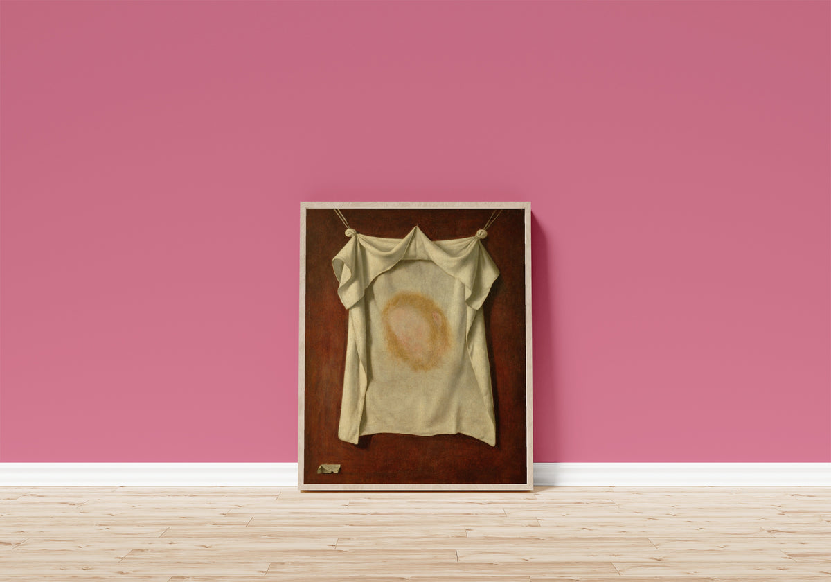 Framed art print of The Holy Face by Francisco de Zurbarán, in a light wood frame leaning on a pink wall above a wooden floor