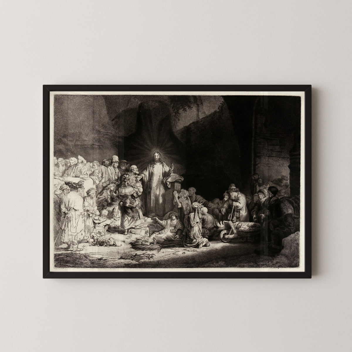 Framed art print of The Hundred Guilder Print by Rembrandt van Rijn, in a black frame on a pale wall