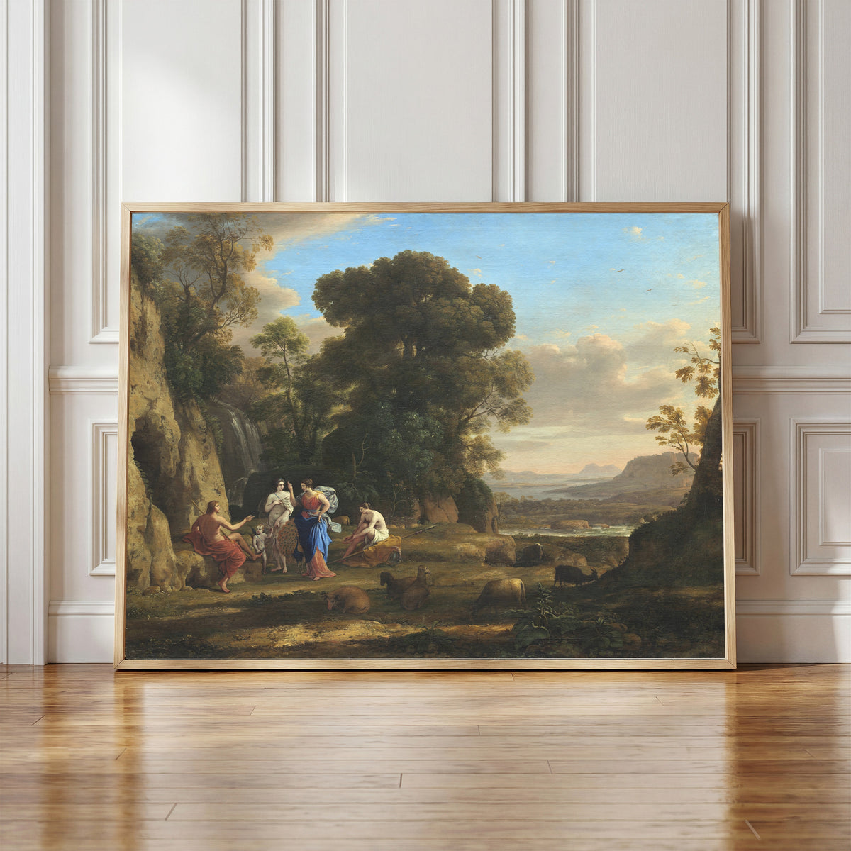Framed art print of The Judgment of Paris by Claude Lorrain, in a light wood frame leaning against a panelled white wall