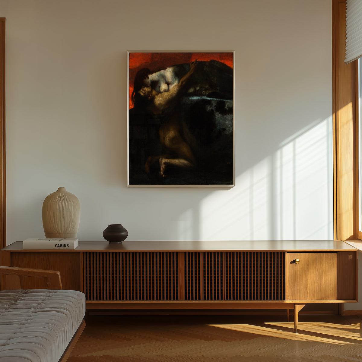 Framed art print of The Kiss of the Sphinx by Franz von Stuck, in a thin light frame on a sunlit wall above a wooden sideboard