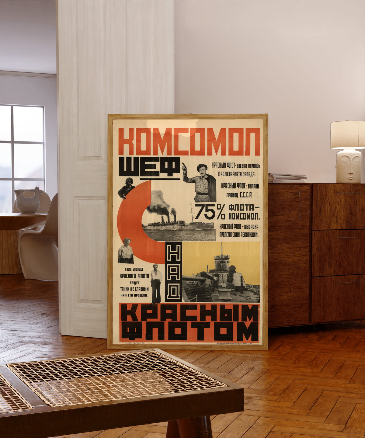 Framed art print of The Komsomol is patron of the Red Fleet, in a light wood frame leaning in a warm room with a parquet floor