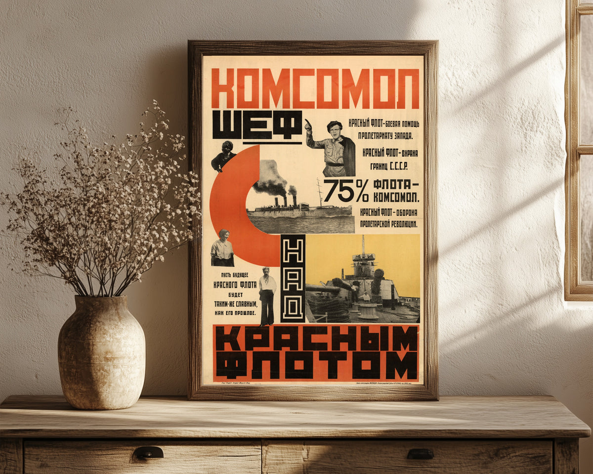 Framed art print of The Komsomol is patron of the Red Fleet, in a dark wood frame leaning on a rustic console beside dried flowers