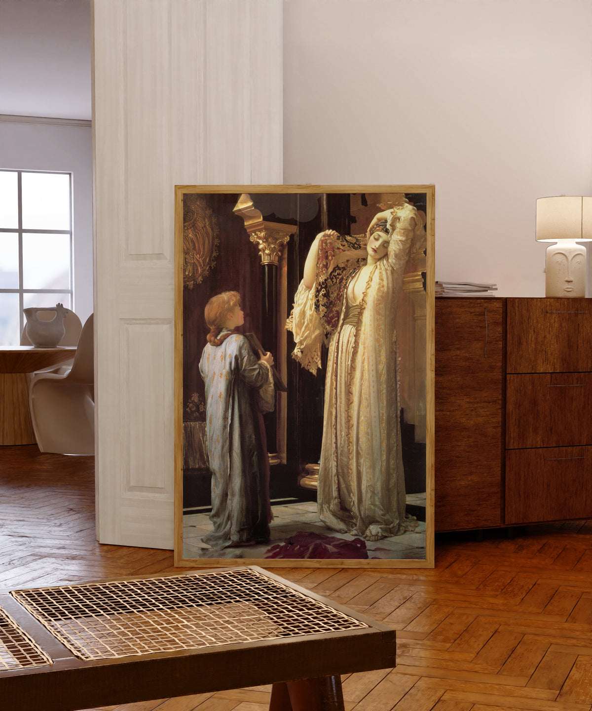 Framed art print of The Light of the Harem by Frederic Leighton, in a light wood frame leaning in a warm room with a parquet floor
