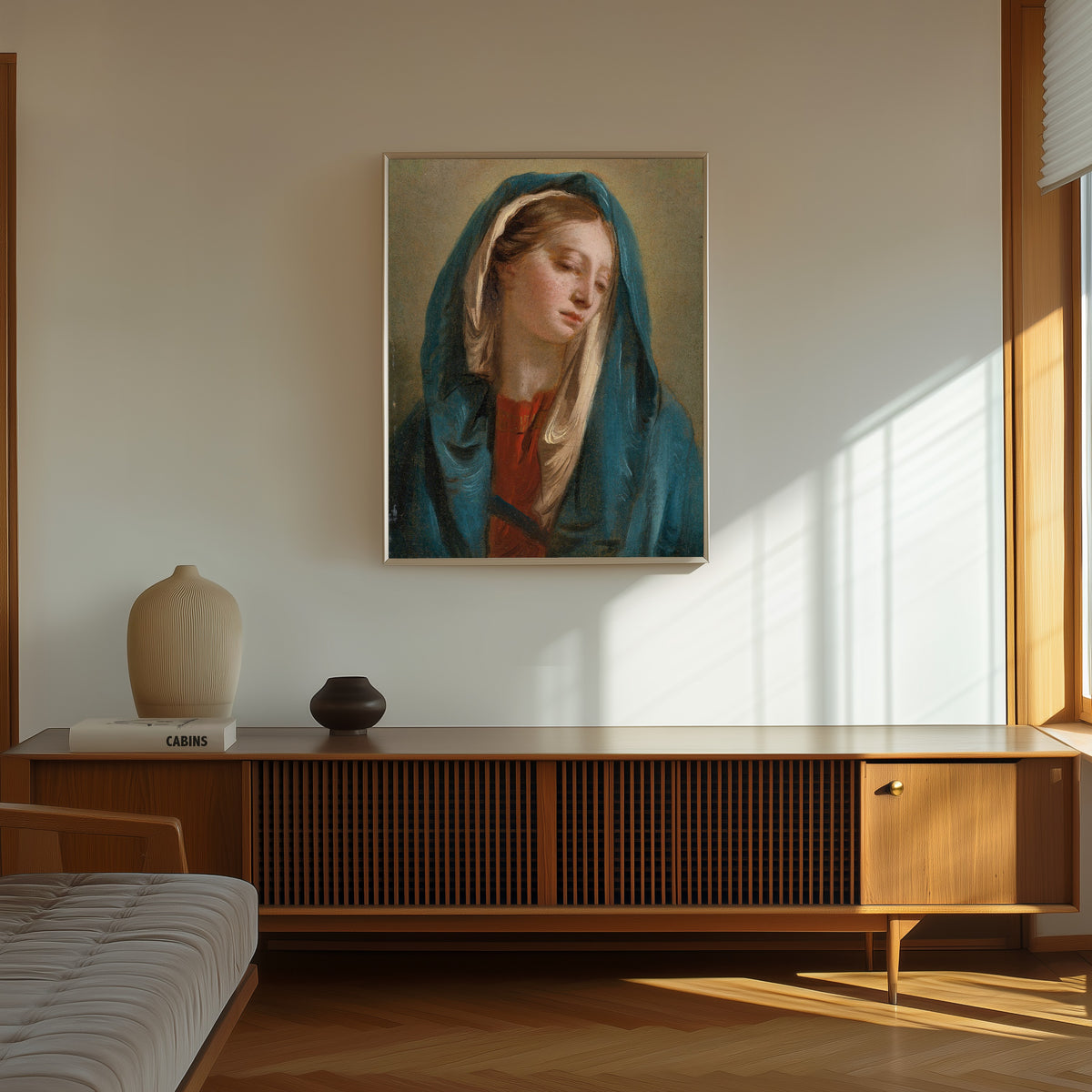 Framed art print of The Madonna Facing Front and Wearing a Blue… by Giovanni Battista Tiepolo, in a thin light frame on a sunlit wall above a wooden sideboard