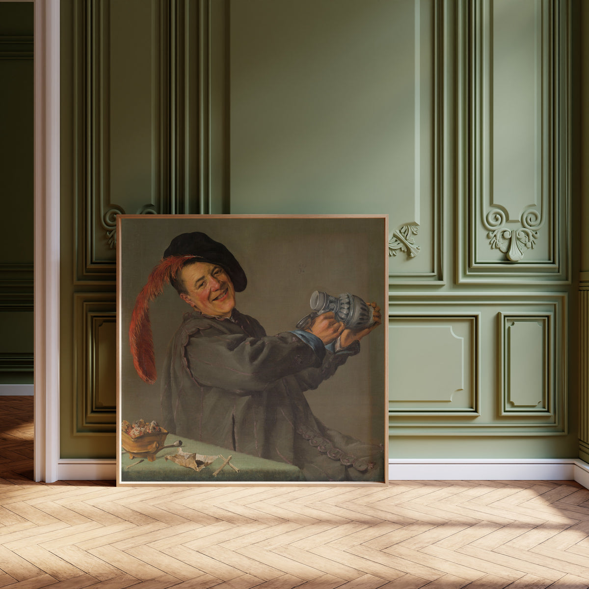 Framed art print of The Merry Drinker by Judith Leyster, leaning against olive-green panelling on a herringbone floor