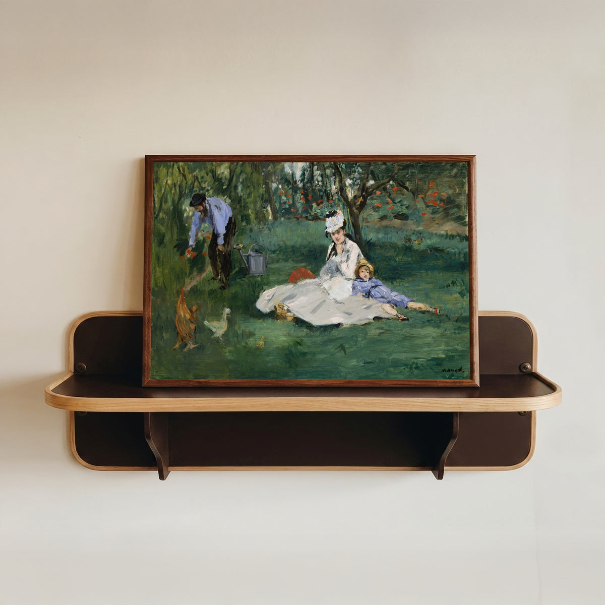 Framed art print of The Monet Family in Their Garden at Argenteuil by Édouard Manet, in a dark wood frame resting on a wall shelf