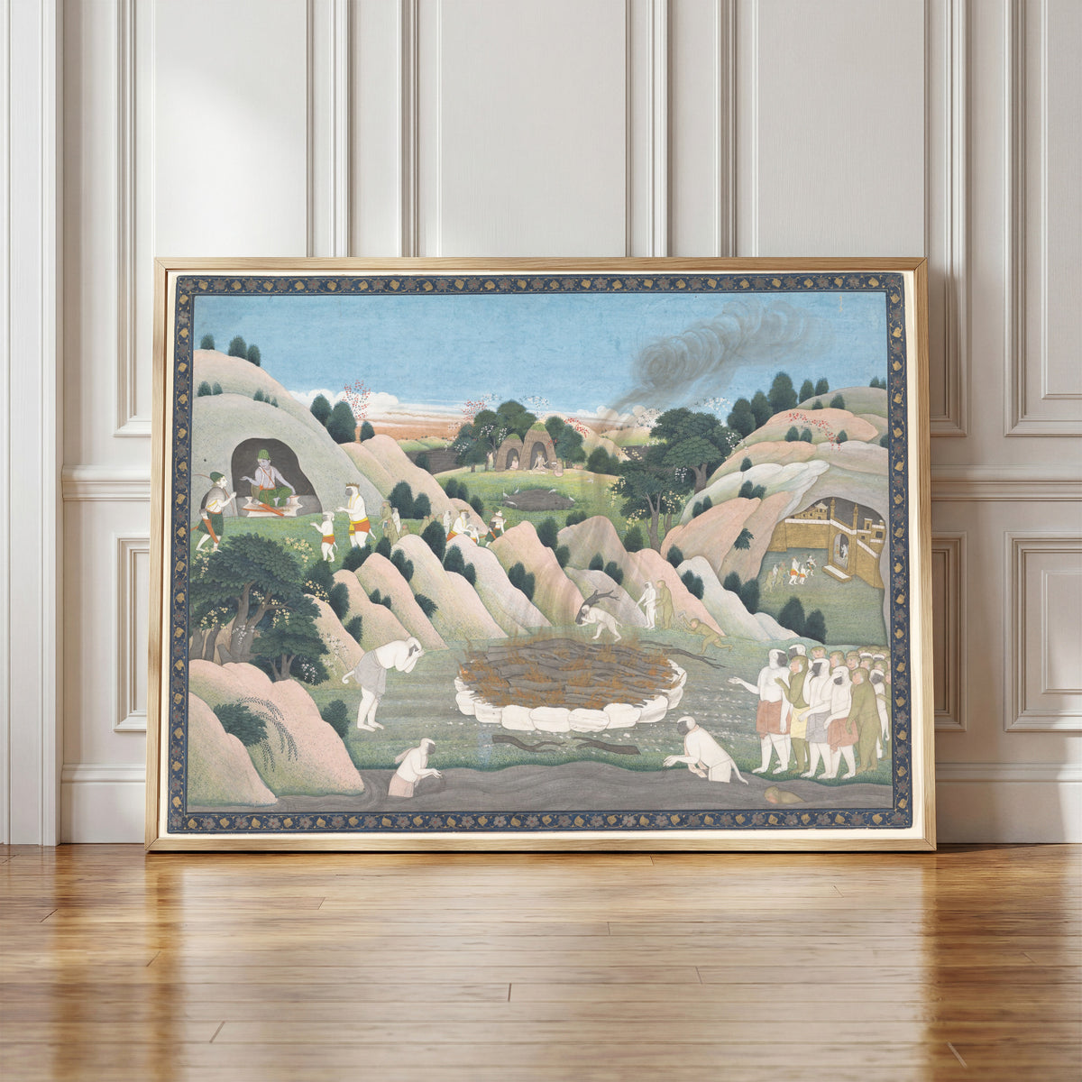 Framed art print of The Monkey King Vali's Funeral Pyre by Kangra school, in a light wood frame leaning against a panelled white wall