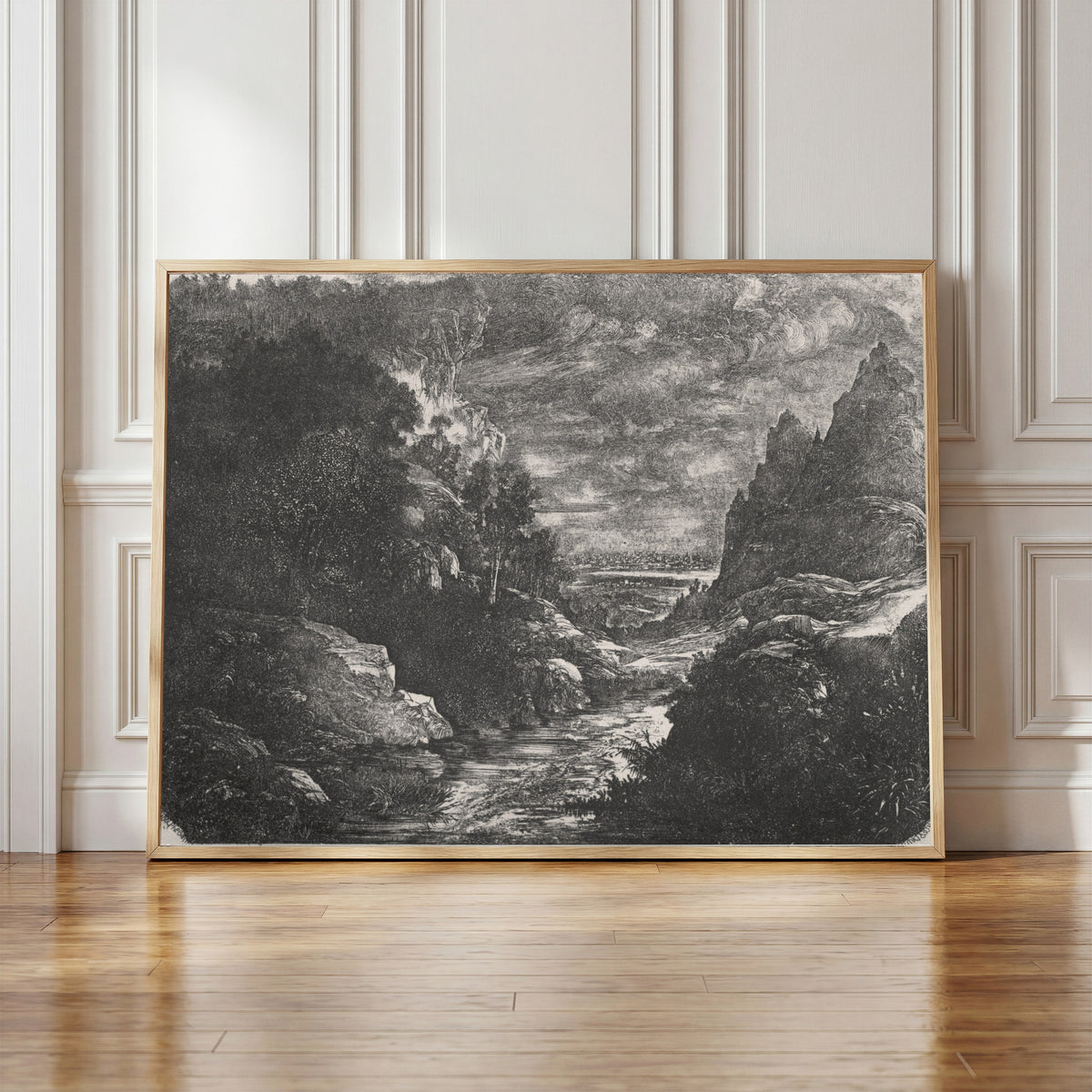Framed art print of The Mountain Stream by Rodolphe Bresdin, in a light wood frame leaning against a panelled white wall