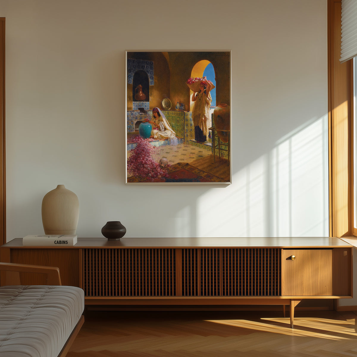 Framed art print of The Perfume Makers by Rudolf Ernst, in a thin light frame on a sunlit wall above a wooden sideboard