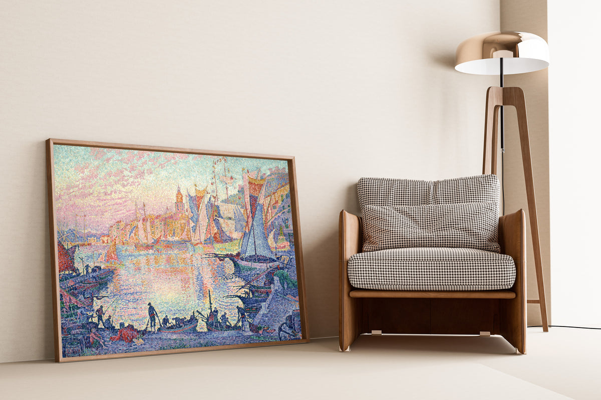 Framed art print of The Port of Saint-Tropez by Paul Signac, leaning against a wall beside an armchair and a floor lamp