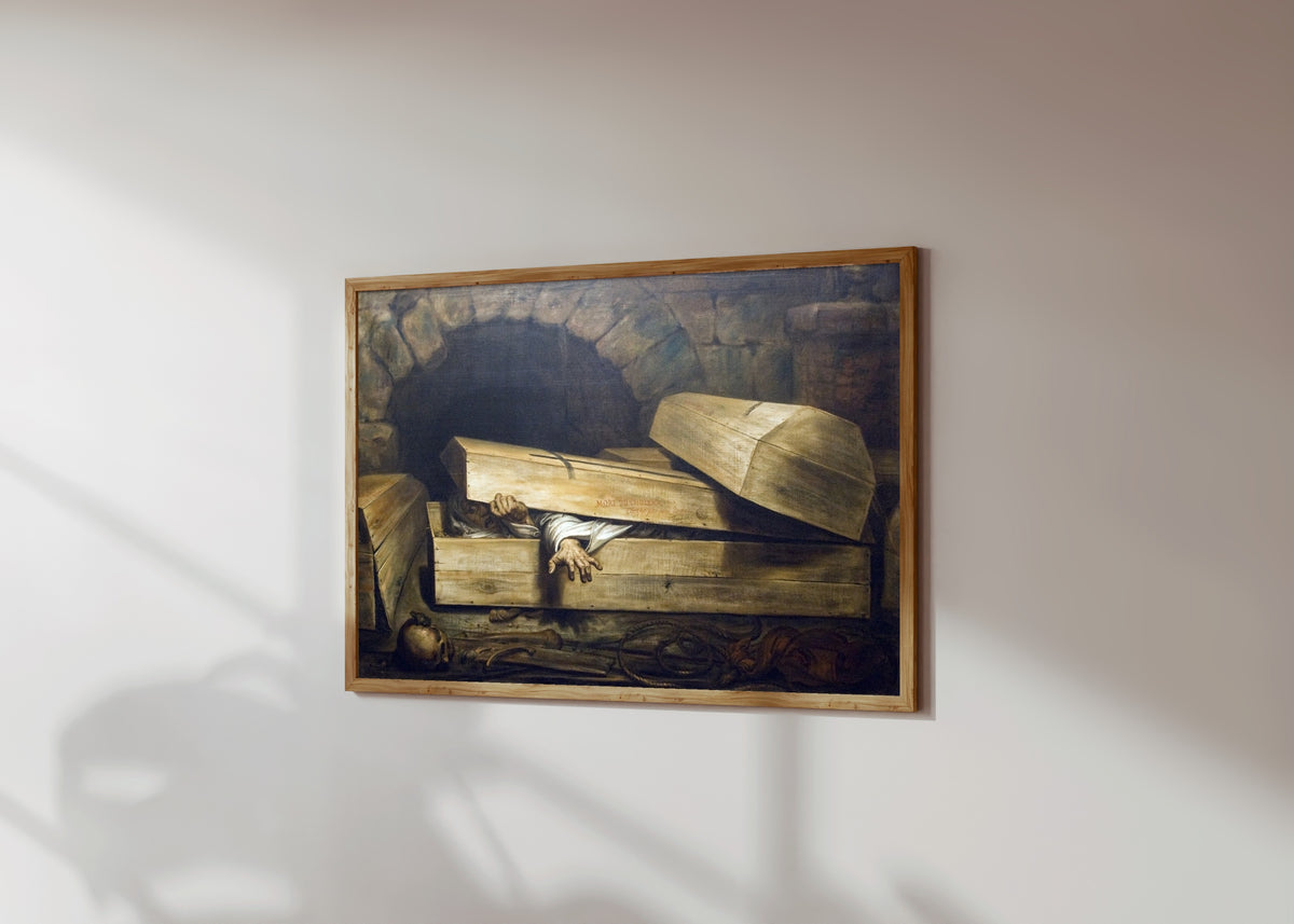 Framed art print of The Premature Burial by Antoine Wiertz, in a light wood frame on a sunlit white wall, seen at a slight angle