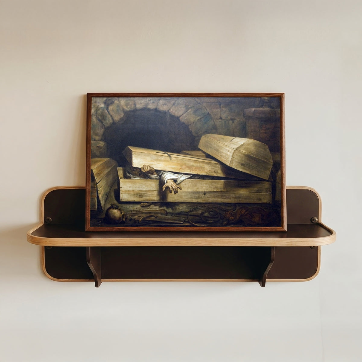 Framed art print of The Premature Burial by Antoine Wiertz, in a dark wood frame resting on a wall shelf