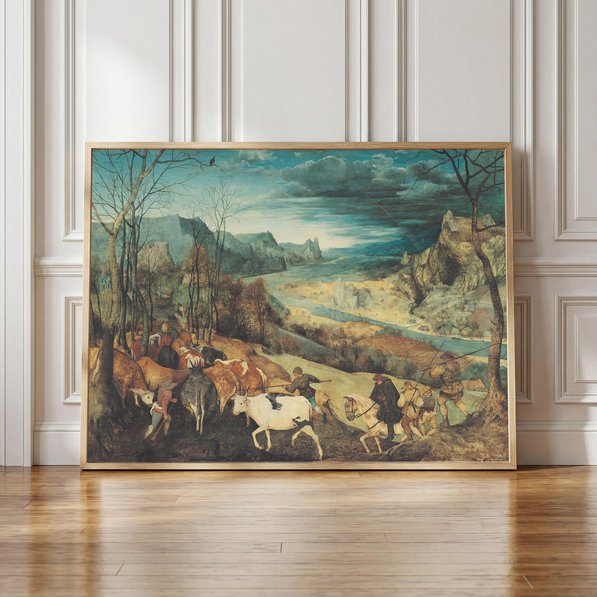 Framed art print of The Return of the Herd (Autumn) by Pieter Bruegel the Elder, in a light wood frame leaning against a panelled white wall