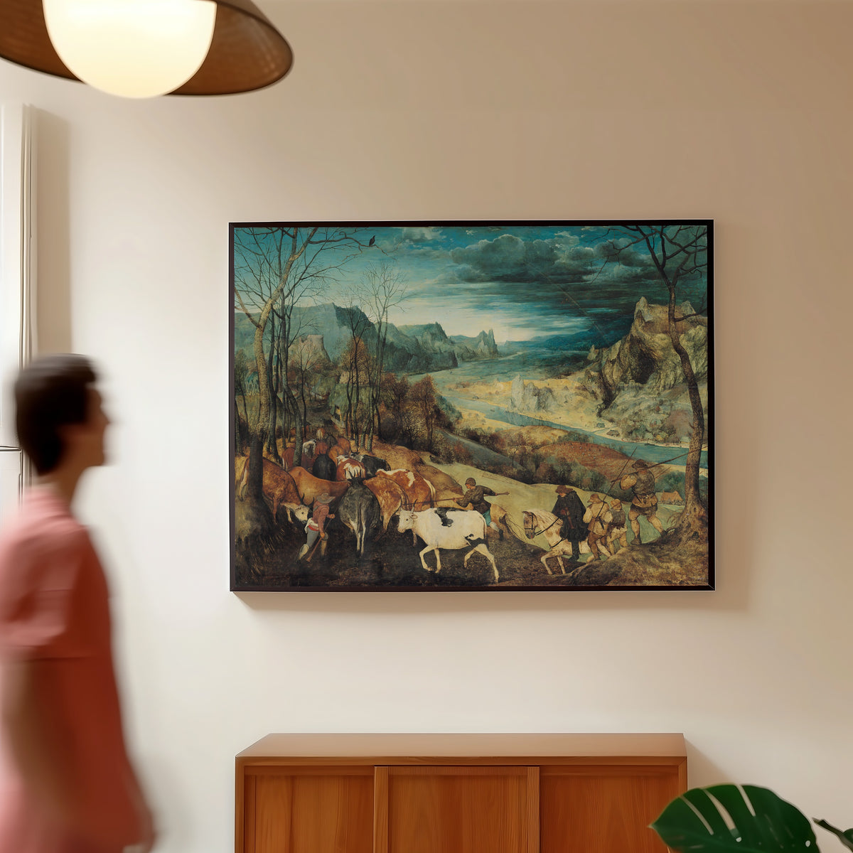 Framed art print of The Return of the Herd (Autumn) by Pieter Bruegel the Elder, in a slim black frame on a warm wall in a sunlit room