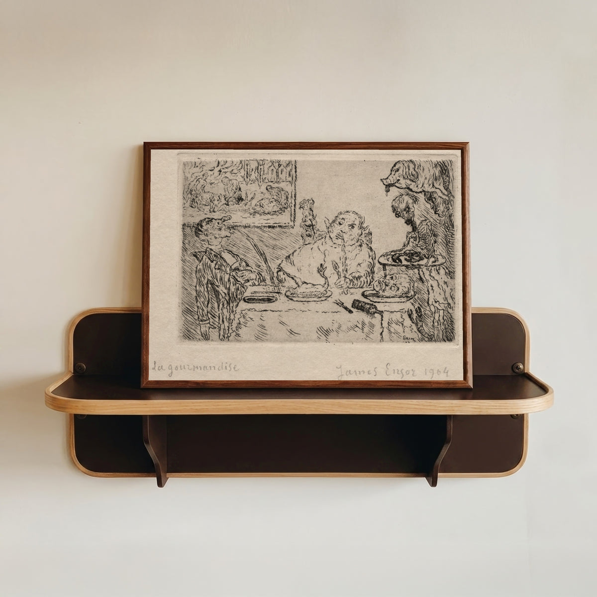 Framed art print of The Seven Deadly Sins: Gluttony by James Ensor, in a dark wood frame resting on a wall shelf