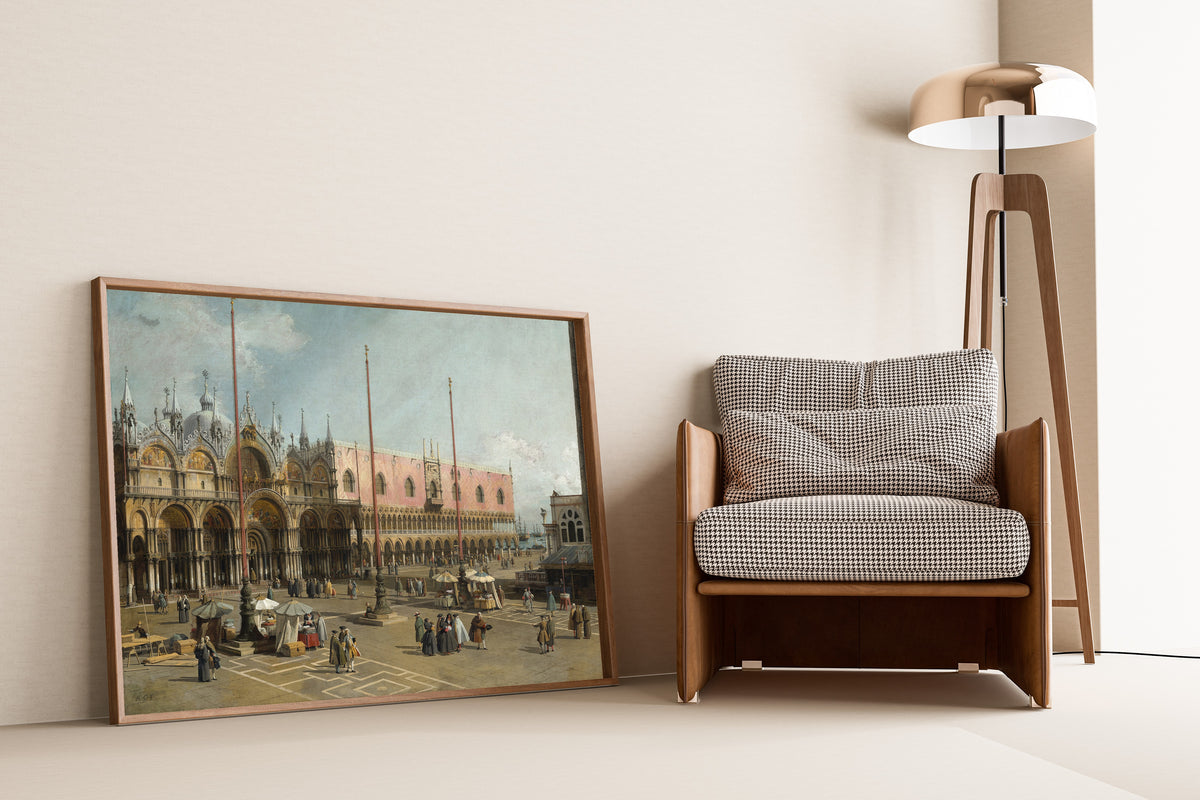 Framed art print of The Square of Saint Mark’s, Venice by Canaletto, leaning against a wall beside an armchair and a floor lamp