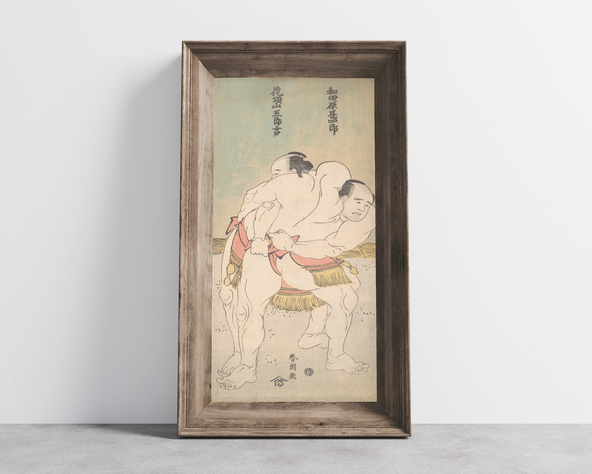 Framed art print of The Sumo Wrestlers Wadagahara Jinshirō and Kachōzan Gorokichi by Katsushika Hokusai, in a wide wooden frame leaning against a concrete wall