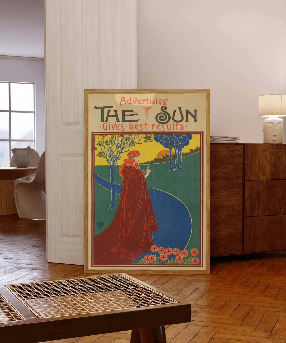 Framed art print of The Sun Gives Good Results by Louis Rhead, in a light wood frame leaning in a warm room with a parquet floor