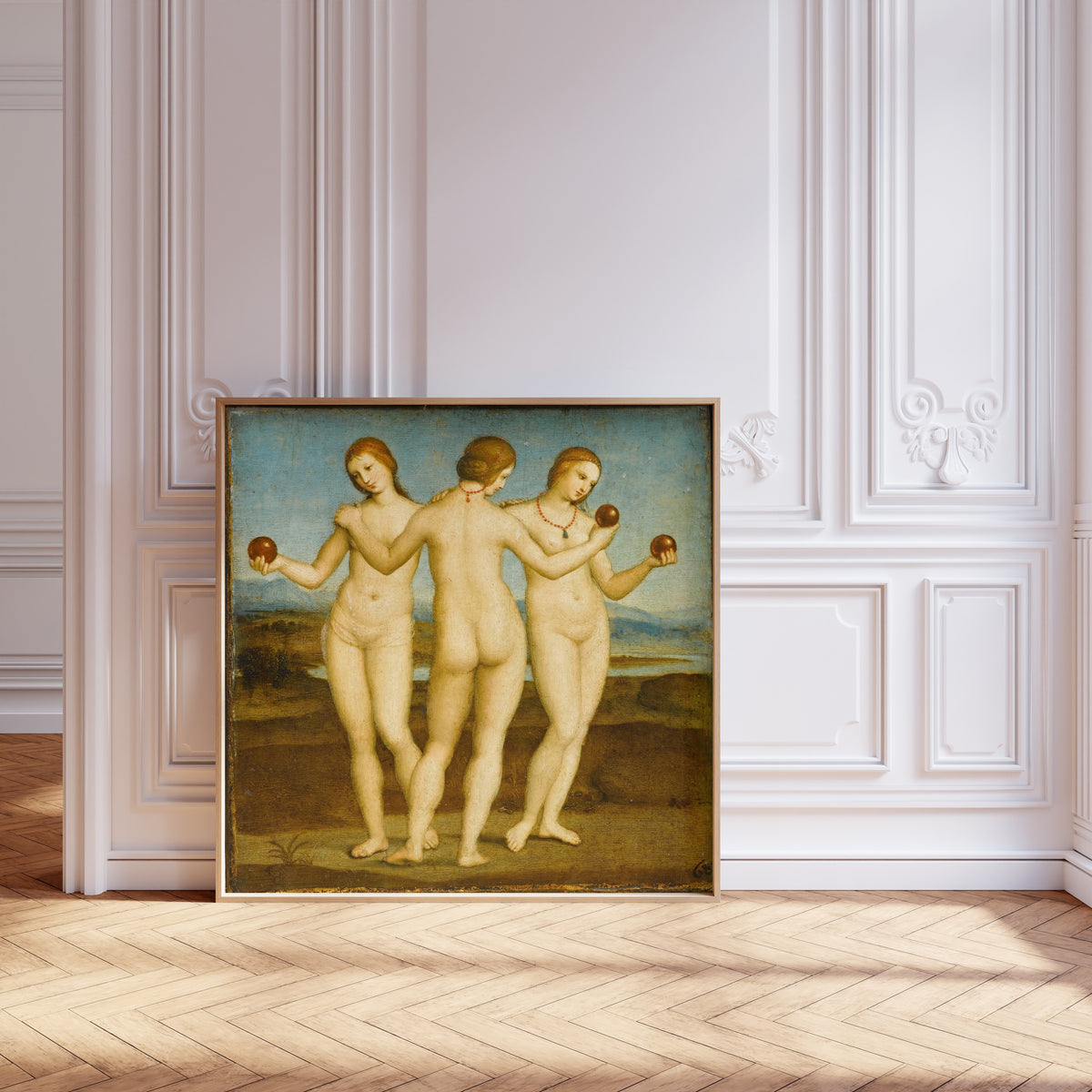 Framed art print of The Three Graces by Raphael, leaning against pale pink panelling on a herringbone floor