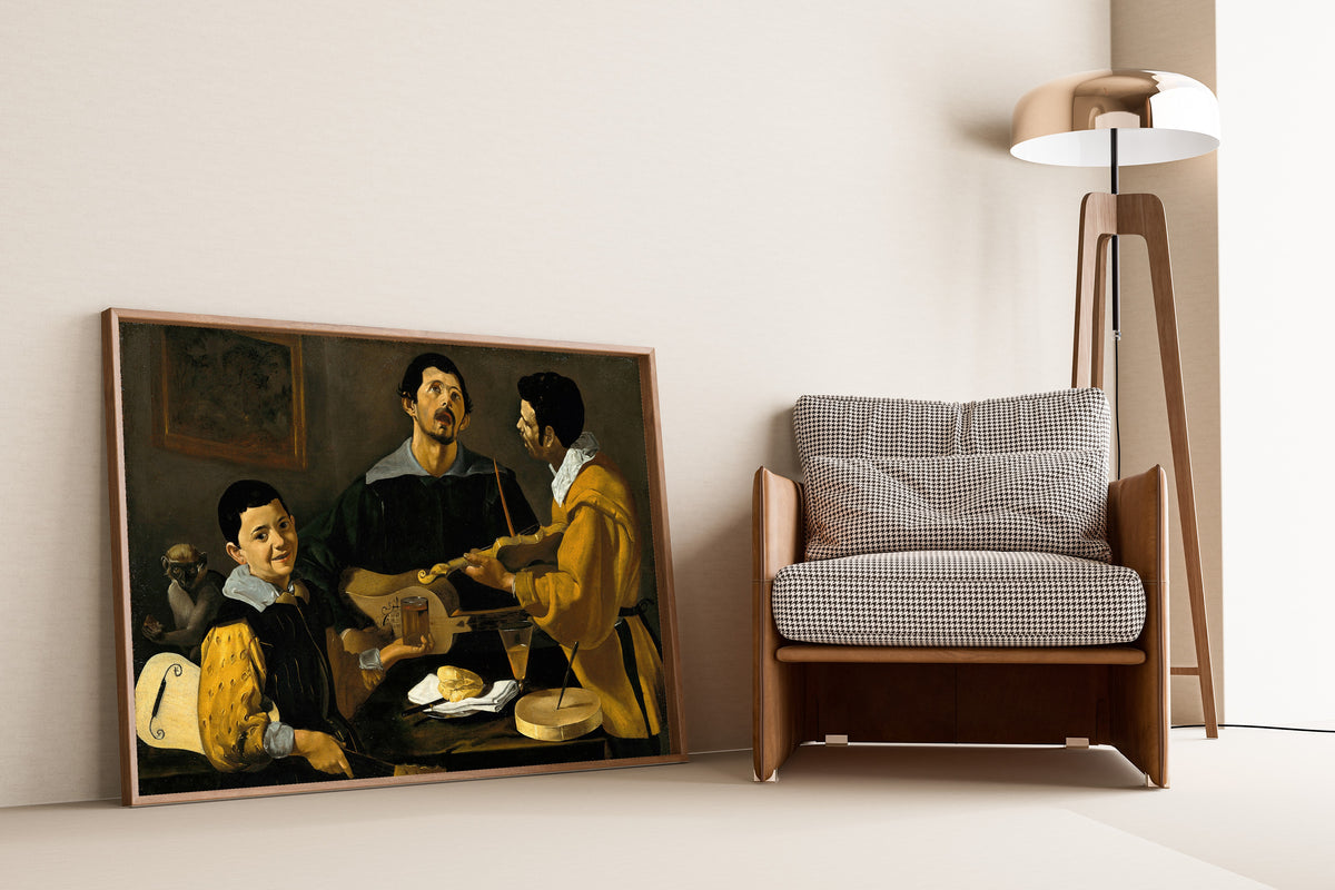 Framed art print of The Three Musicians by Diego Velázquez, leaning against a wall beside an armchair and a floor lamp