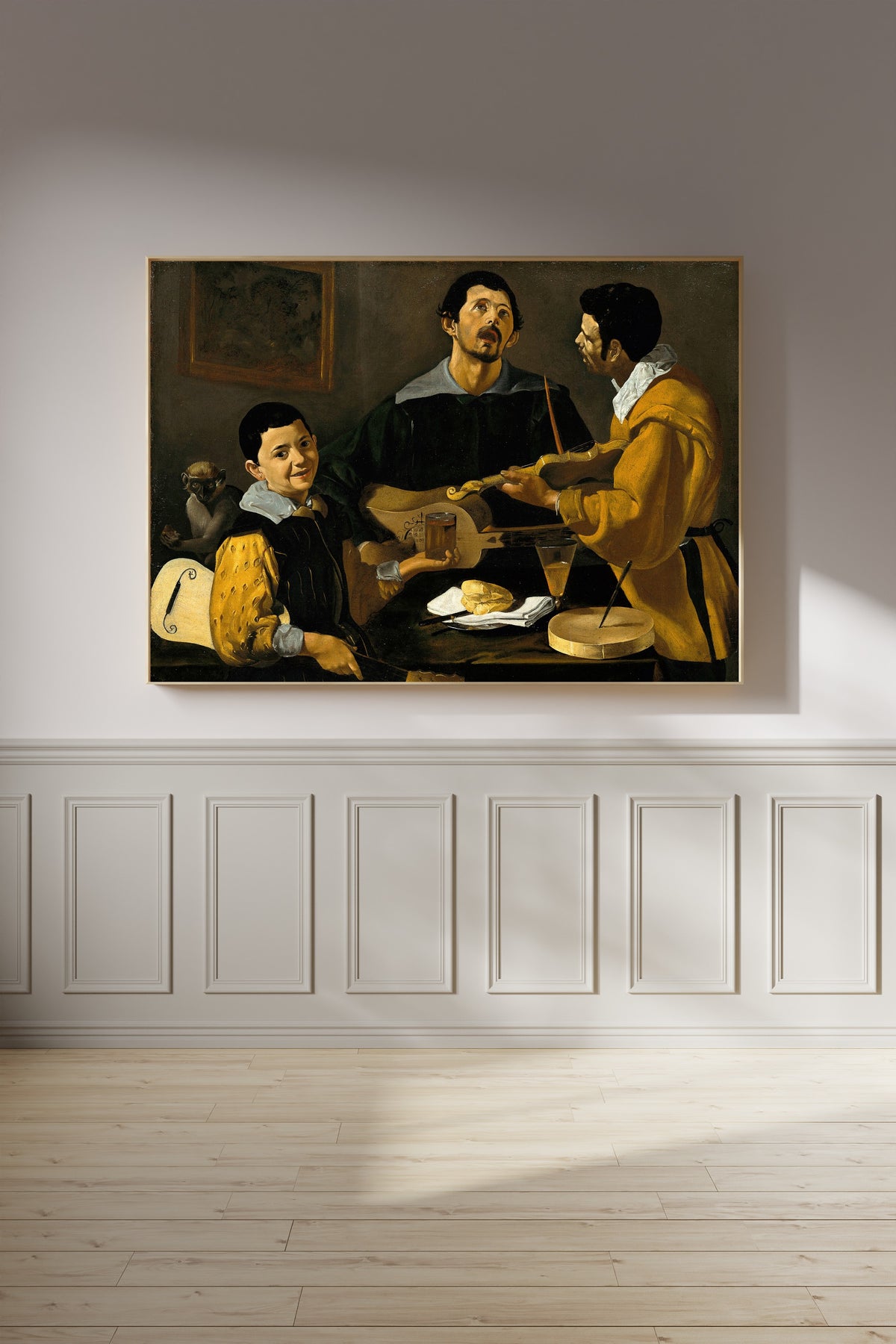 Framed art print of The Three Musicians by Diego Velázquez, on a panelled wall in afternoon light