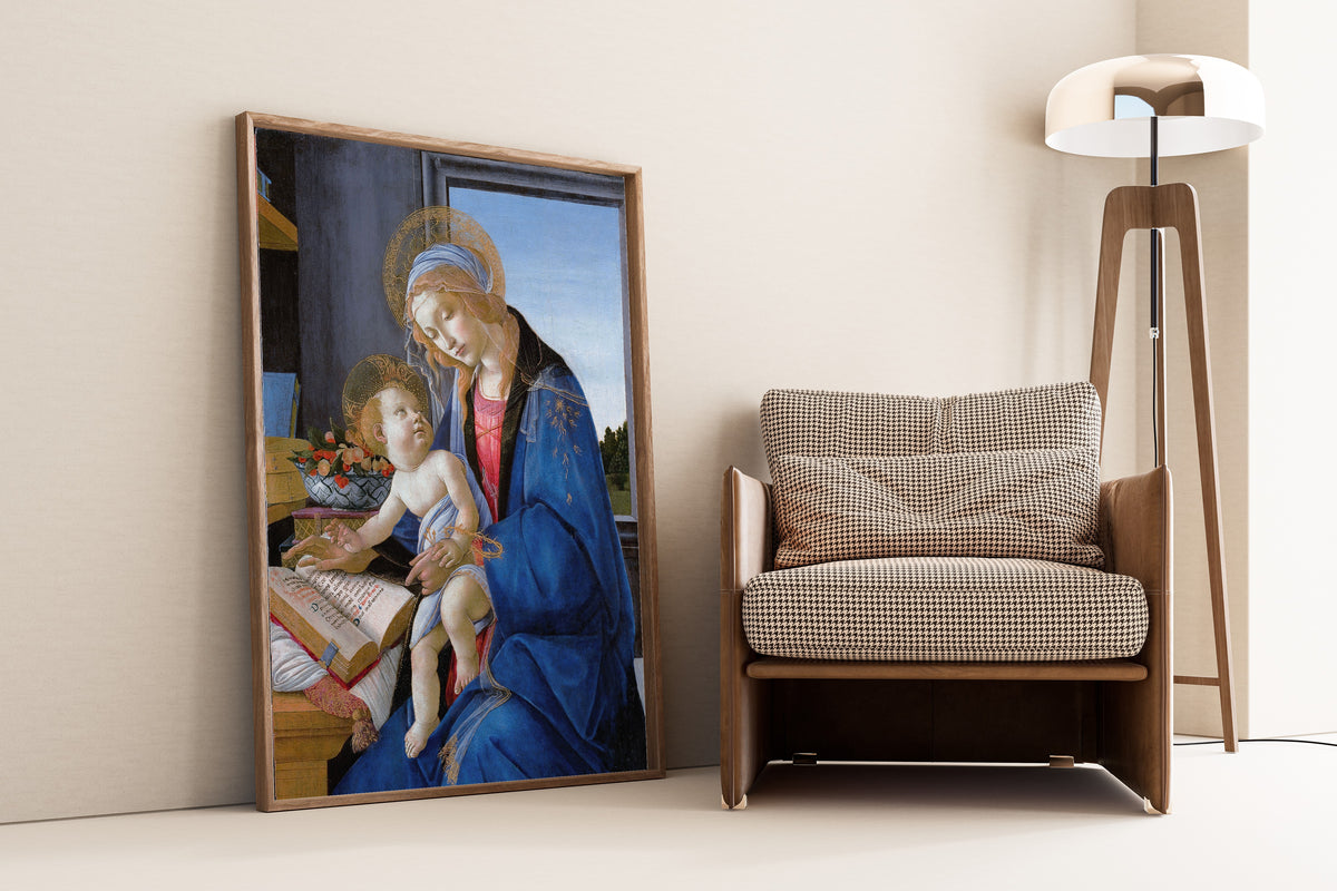 Framed art print of The Virgin and Child (The Madonna of the Book) by Sandro Botticelli, leaning against a wall beside an armchair and a floor lamp