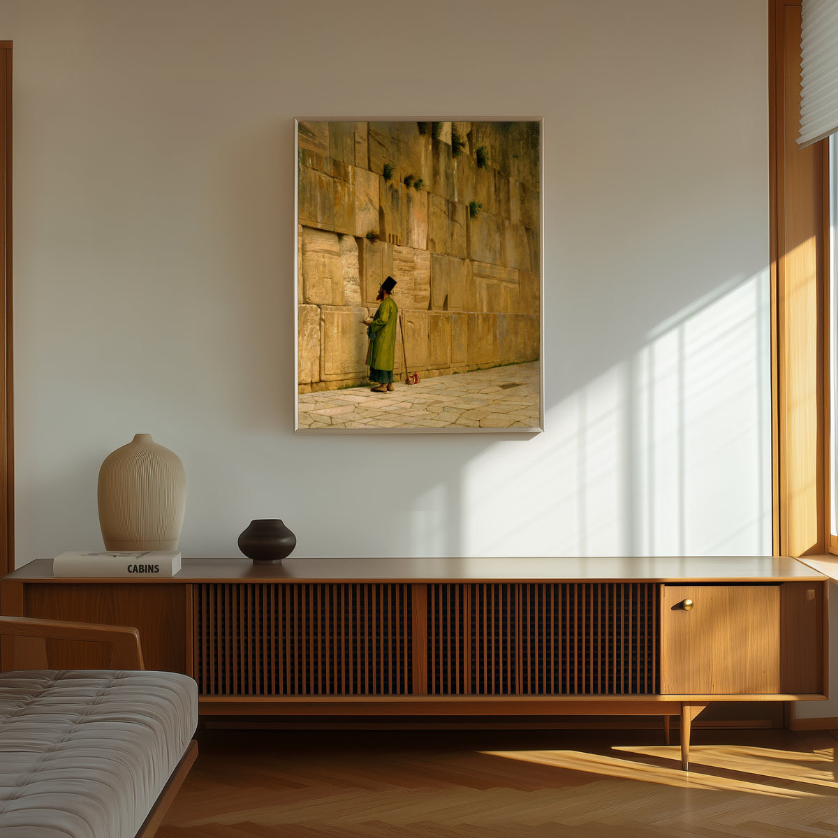 Framed art print of The Wailing Wall by Jean-Léon Gérôme, in a thin light frame on a sunlit wall above a wooden sideboard
