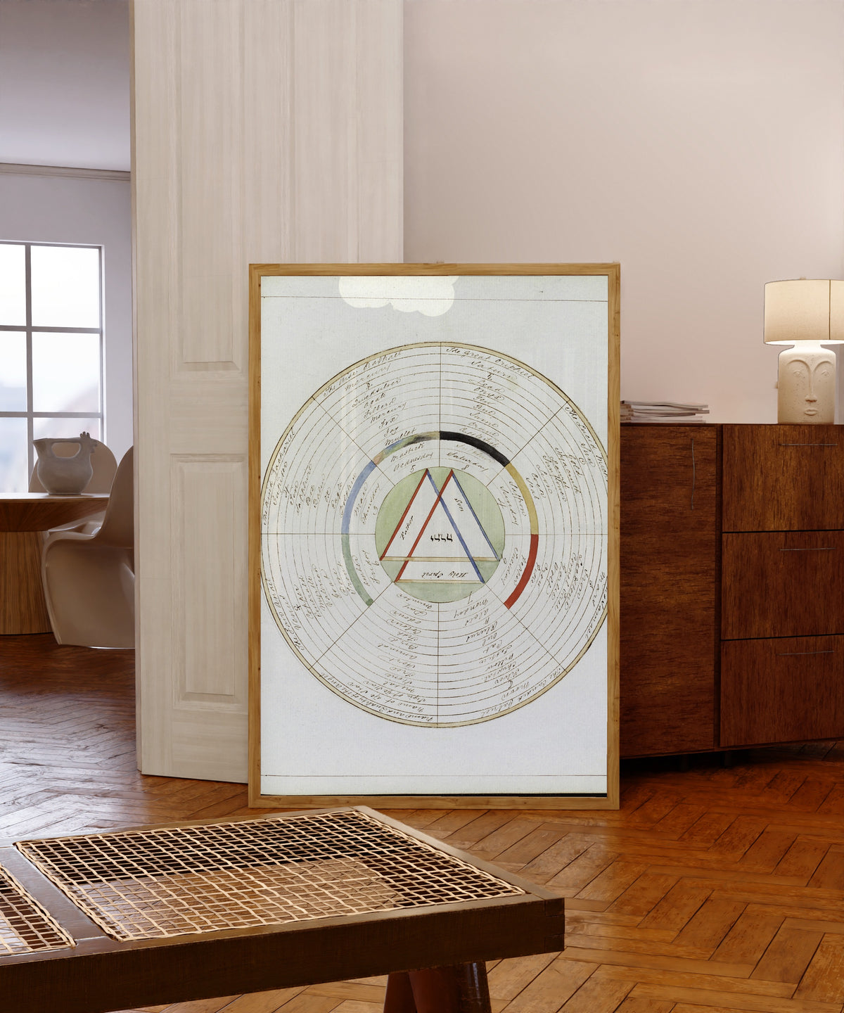 Framed art print of The Wheel of Wisdom, a Magical Treatise by Henry Dawson Lea, in a light wood frame leaning in a warm room with a parquet floor