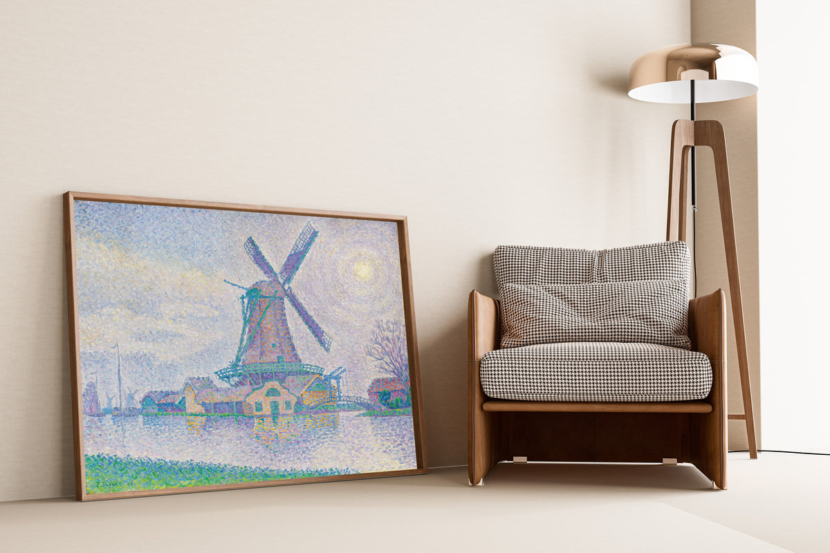 Framed art print of The Windmill at Edam by Paul Signac, leaning against a wall beside an armchair and a floor lamp
