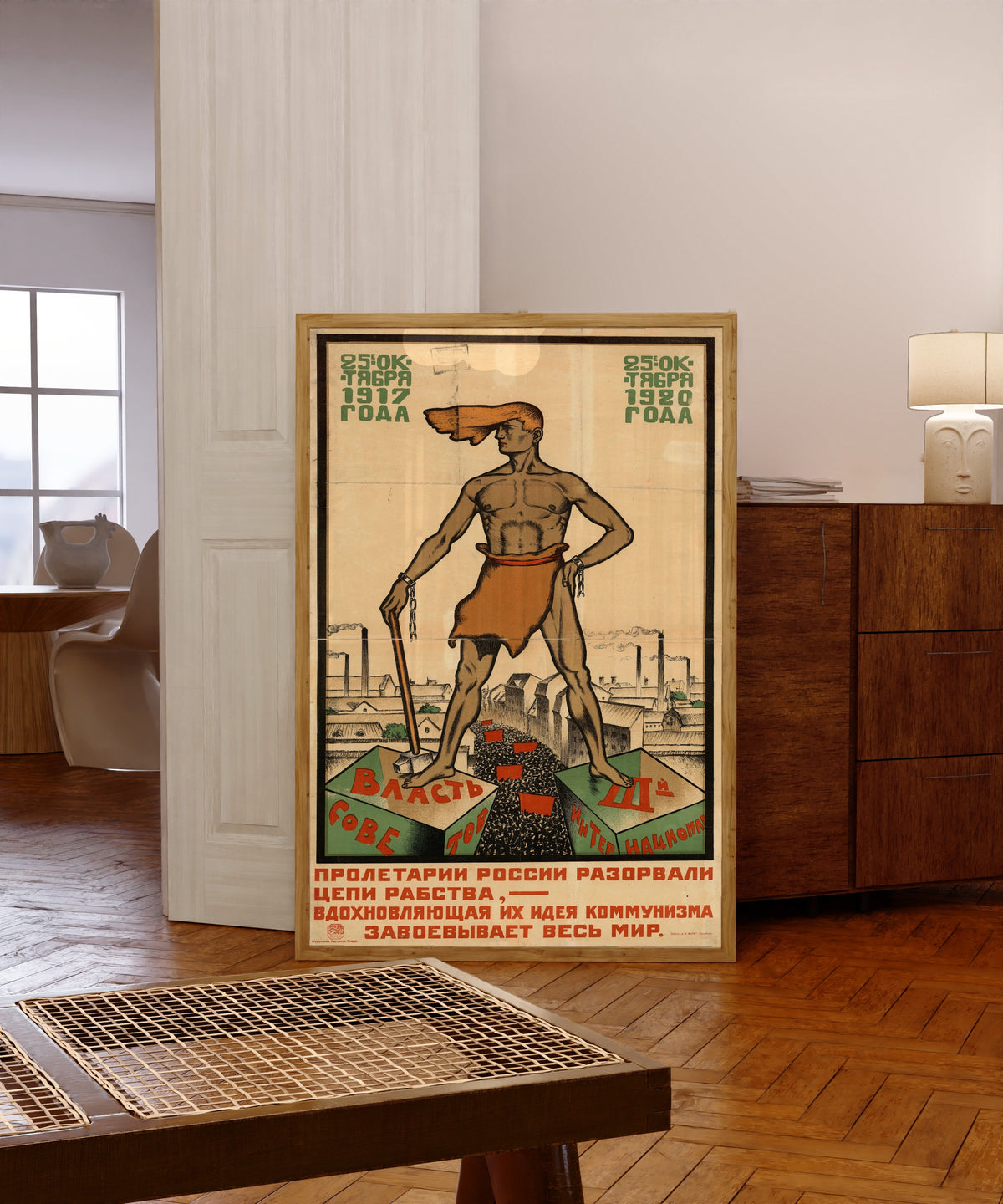 Framed art print of The proletarians of Russia have broken the chains of… by Sergey Ivanov, in a light wood frame leaning in a warm room with a parquet floor