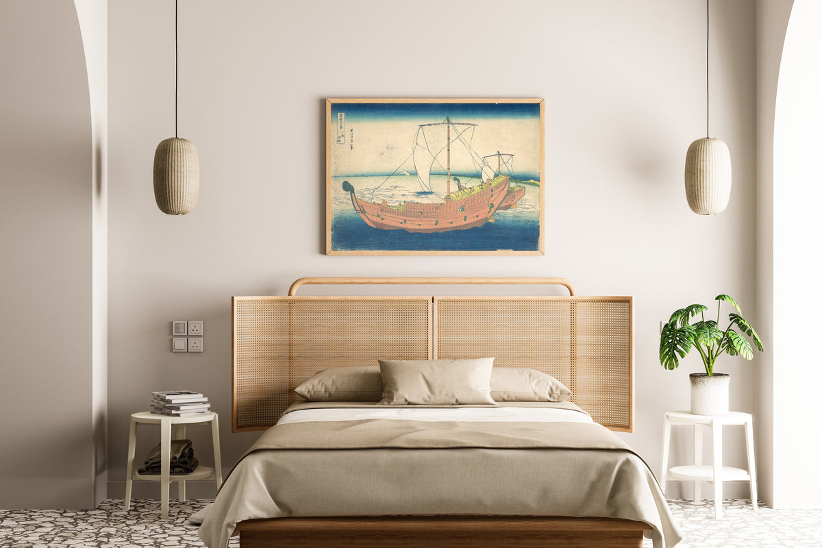 Framed art print of Thirty-six Views of Mount Fuji: At Sea off Kazusa by Katsushika Hokusai, above a cane-headboard bed