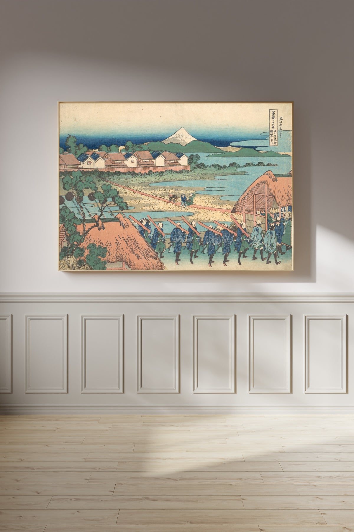 Framed art print of Thirty-six Views of Mount Fuji: Fuji Seen in the Distance from Senju Pleasure… by Katsushika Hokusai, on a panelled wall in afternoon light