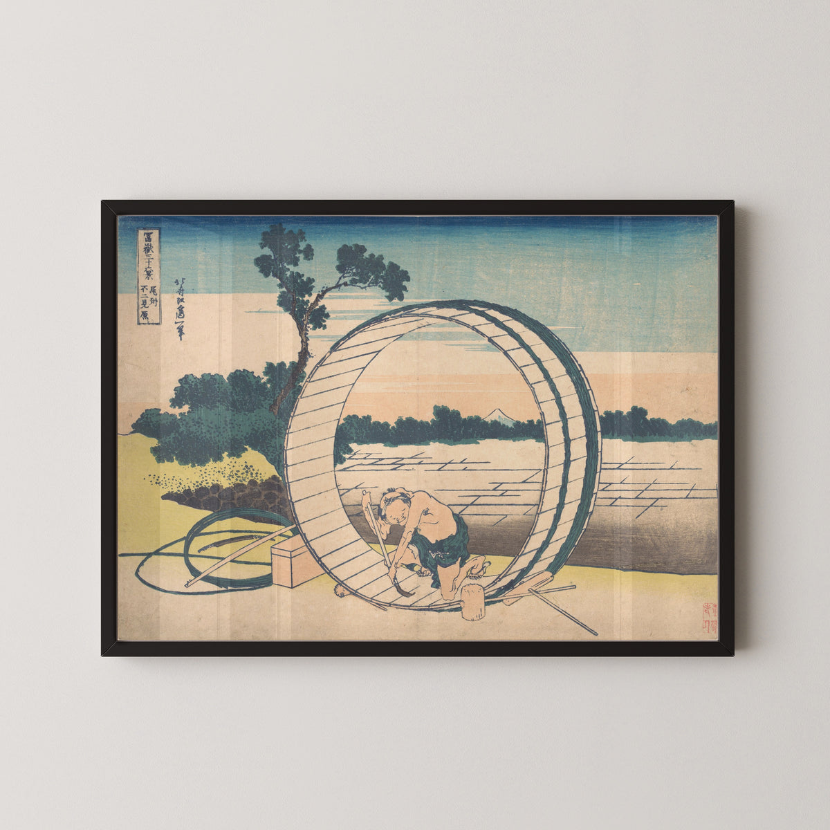 Framed art print of Thirty-six Views of Mount Fuji: Fujimigahara in Owari Province by Katsushika Hokusai, in a black frame on a pale wall