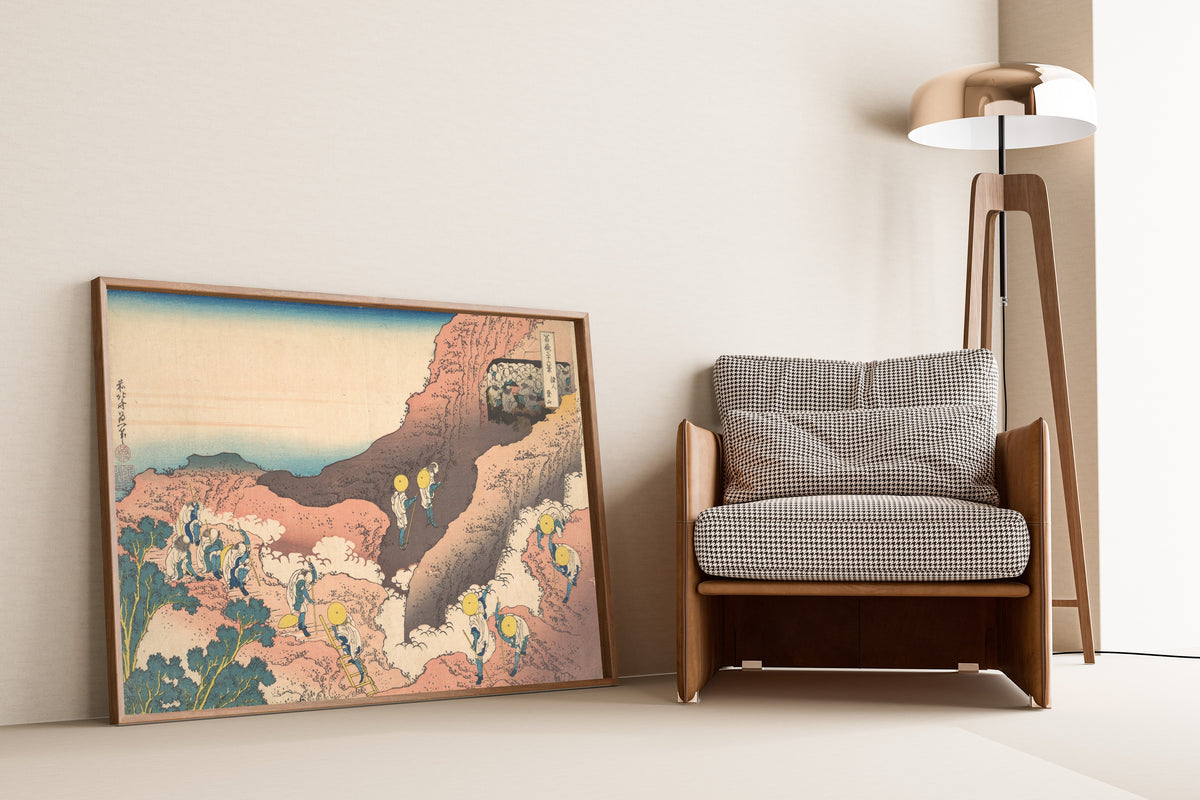 Framed art print of Thirty-six Views of Mount Fuji: Groups of Mountain… by Katsushika Hokusai, leaning against a wall beside an armchair and a floor lamp