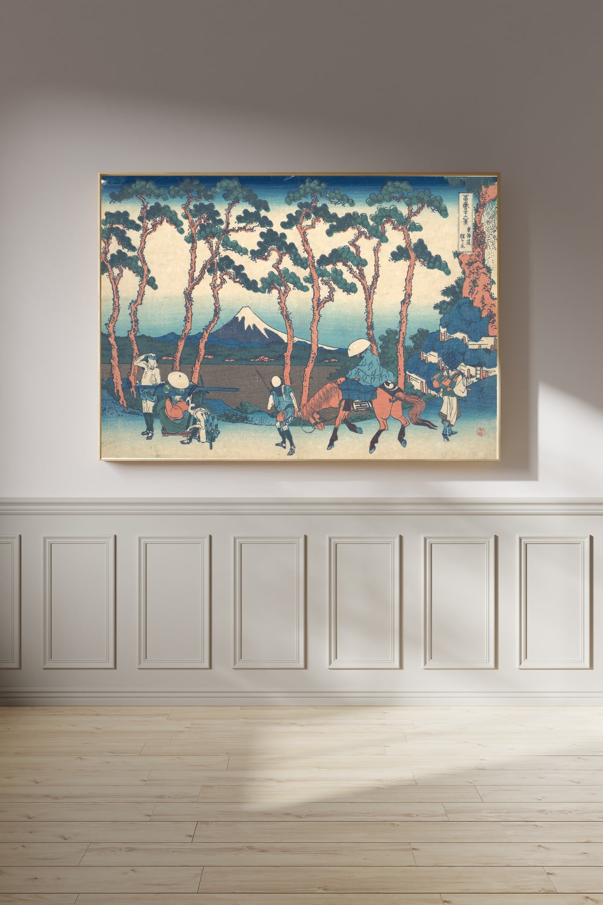 Framed art print of Thirty-six Views of Mount Fuji: Hodogaya on the Tōkaidō by Katsushika Hokusai, on a panelled wall in afternoon light