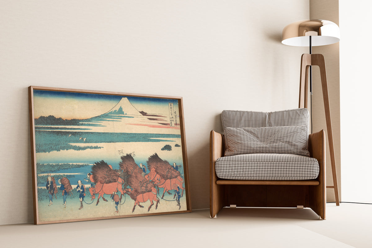 Framed art print of Thirty-six Views of Mount Fuji: The New Fields at Ōno in… by Katsushika Hokusai, leaning against a wall beside an armchair and a floor lamp